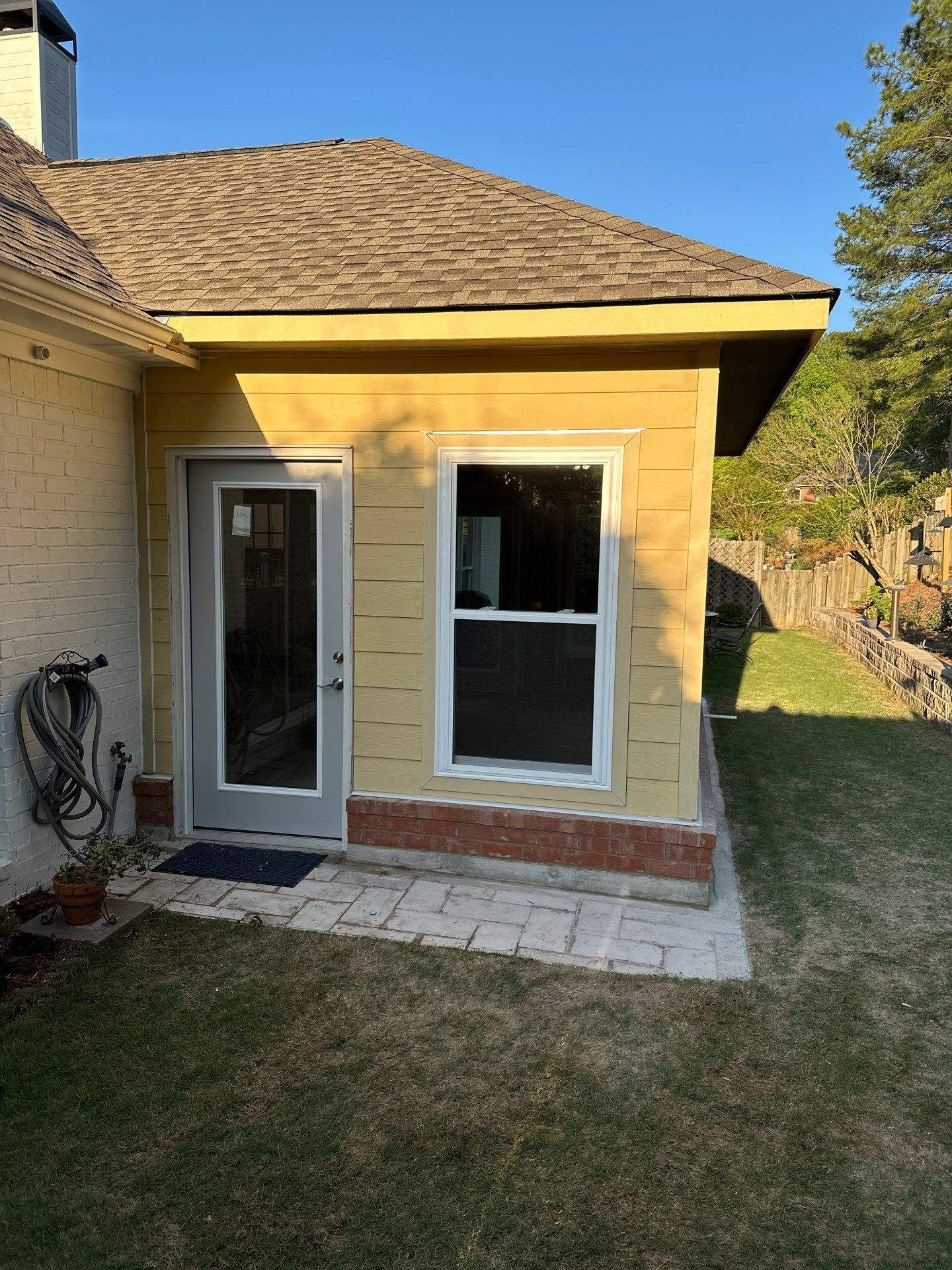 A yellow home addition with new siding, a door, and a window at a residence in the Greystone neighborhood of Hoover.