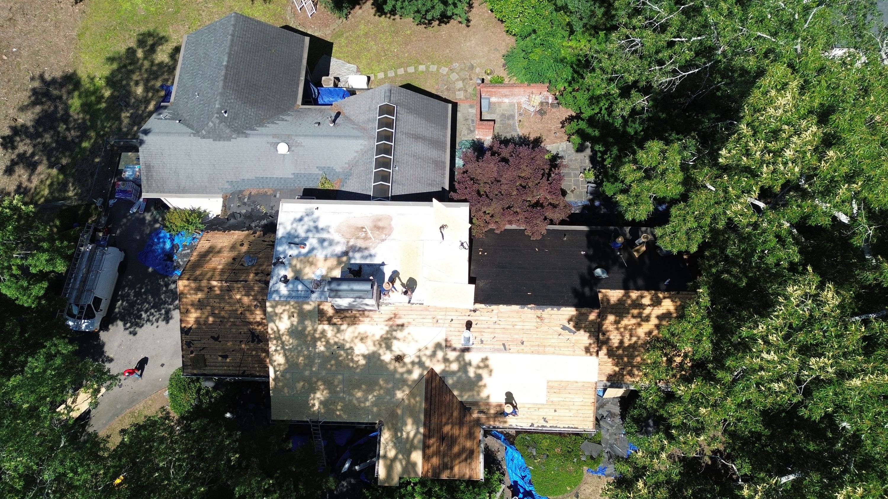 Active roof replacement showing exposed plywood decking and flat roofing on a home in Mountain Brook.