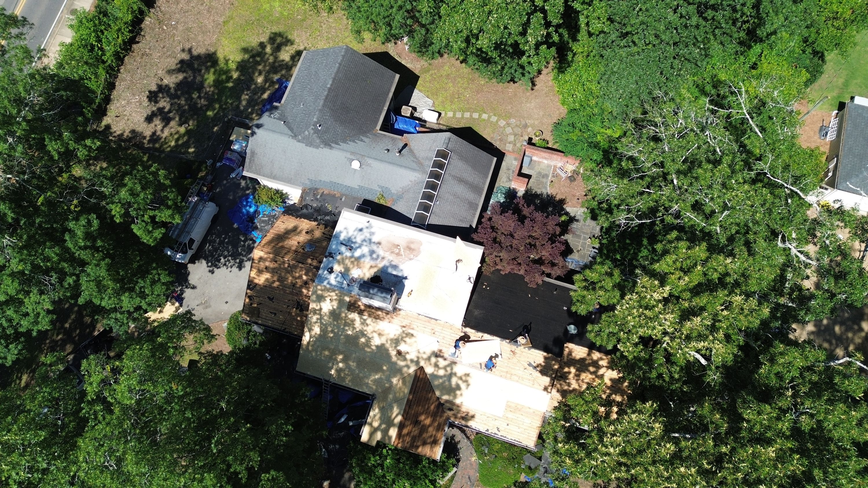Roof replacement progress showing plywood decking and flat roofing on a home in Mountain Brook.