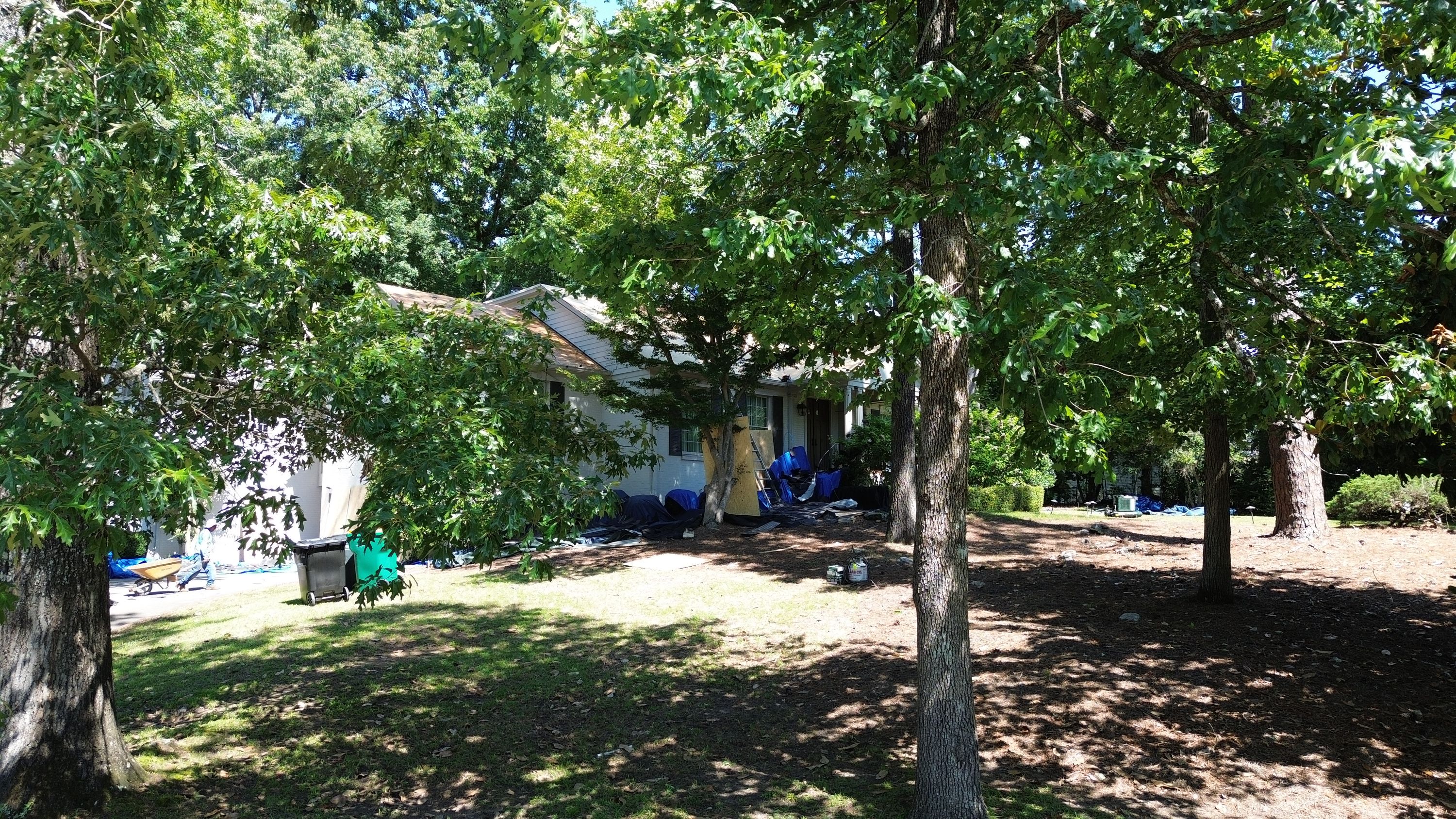 A home in Mountain Brook prepared for a shingle roofing replacement with protective tarps on the ground.