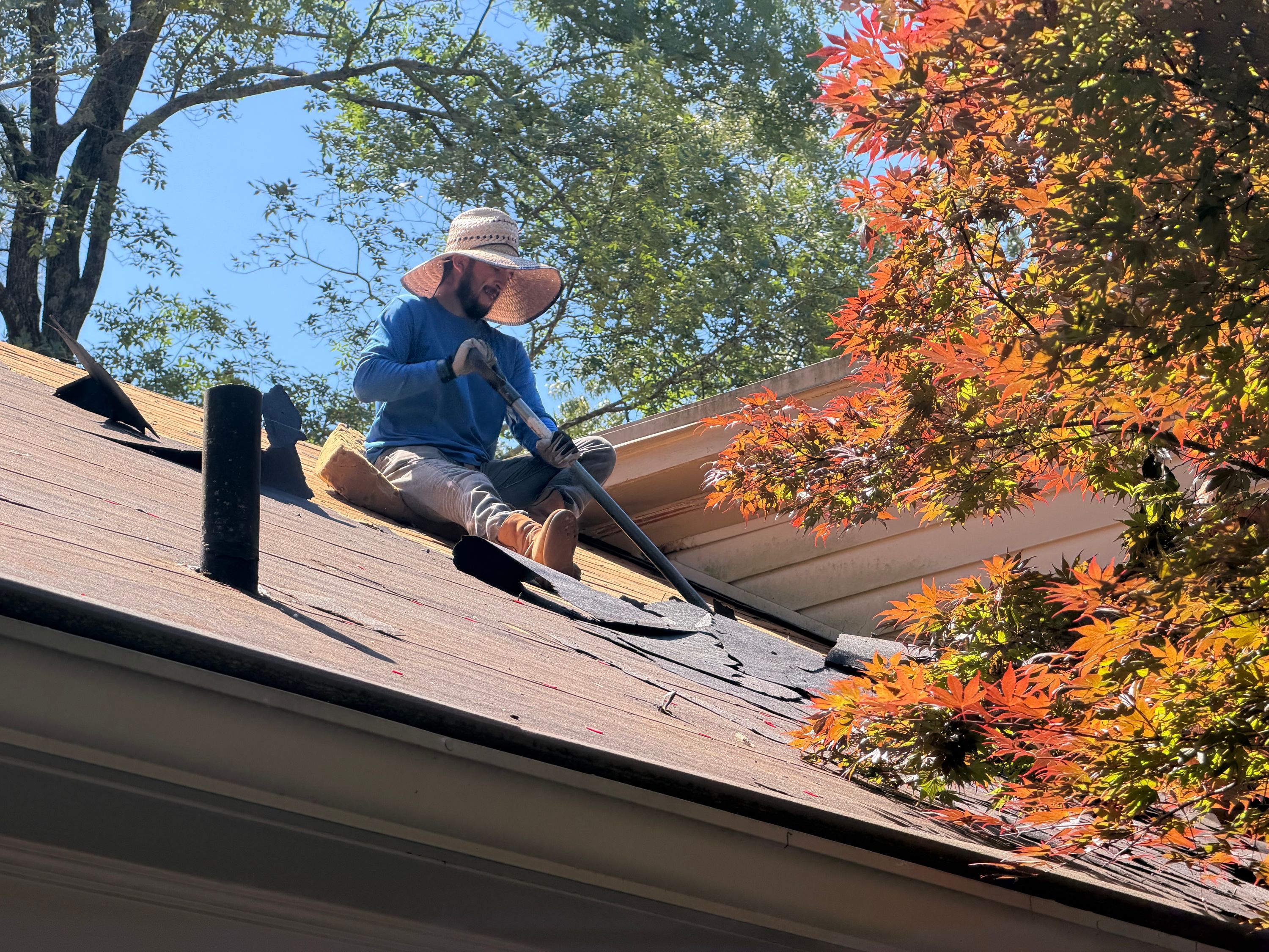 Stripping away old asphalt shingles during a residential roof replacement in Mountain Brook.