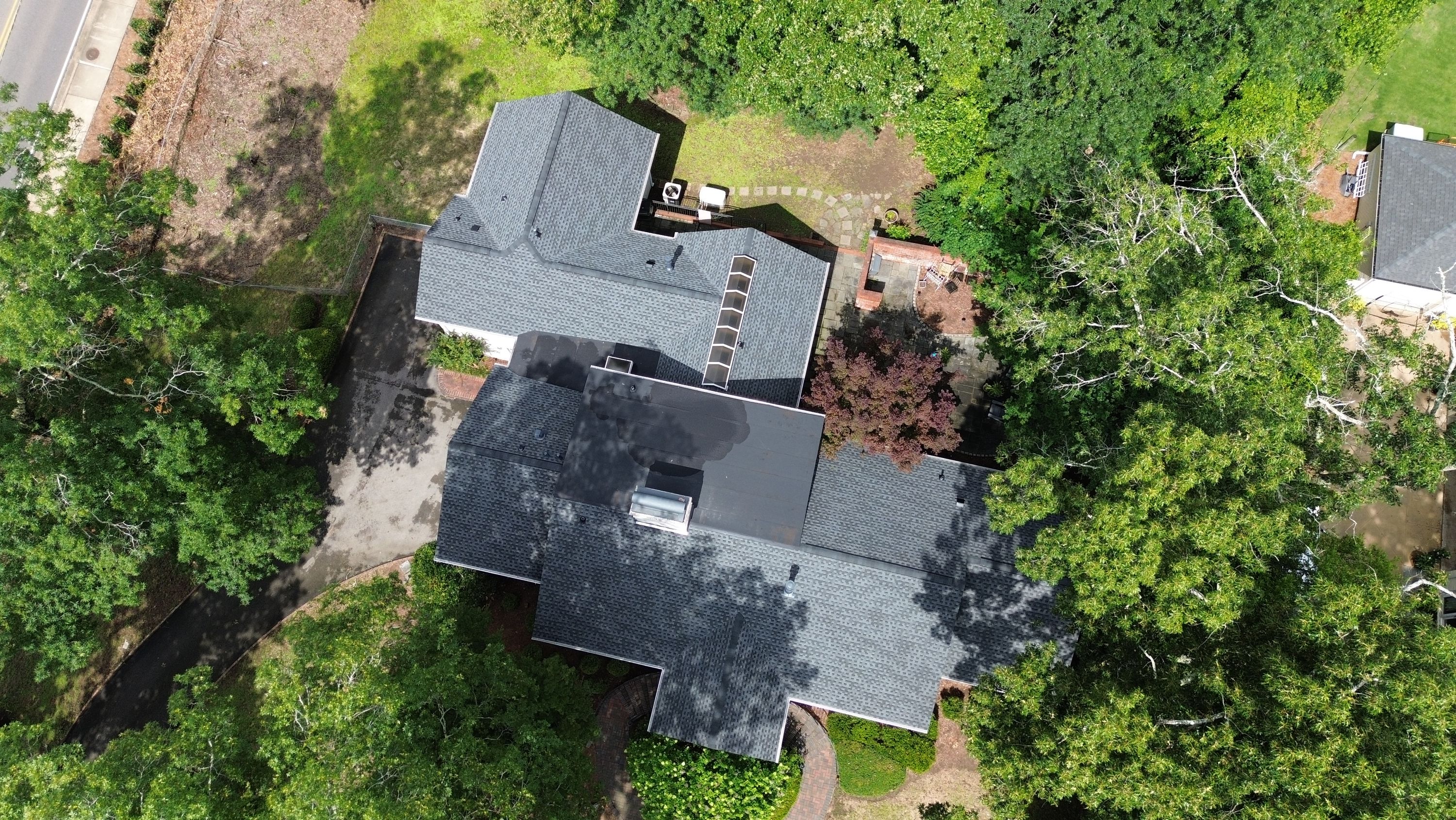 Aerial view of a completed shingle and flat roof replacement with skylights on a home in Mountain Brook.