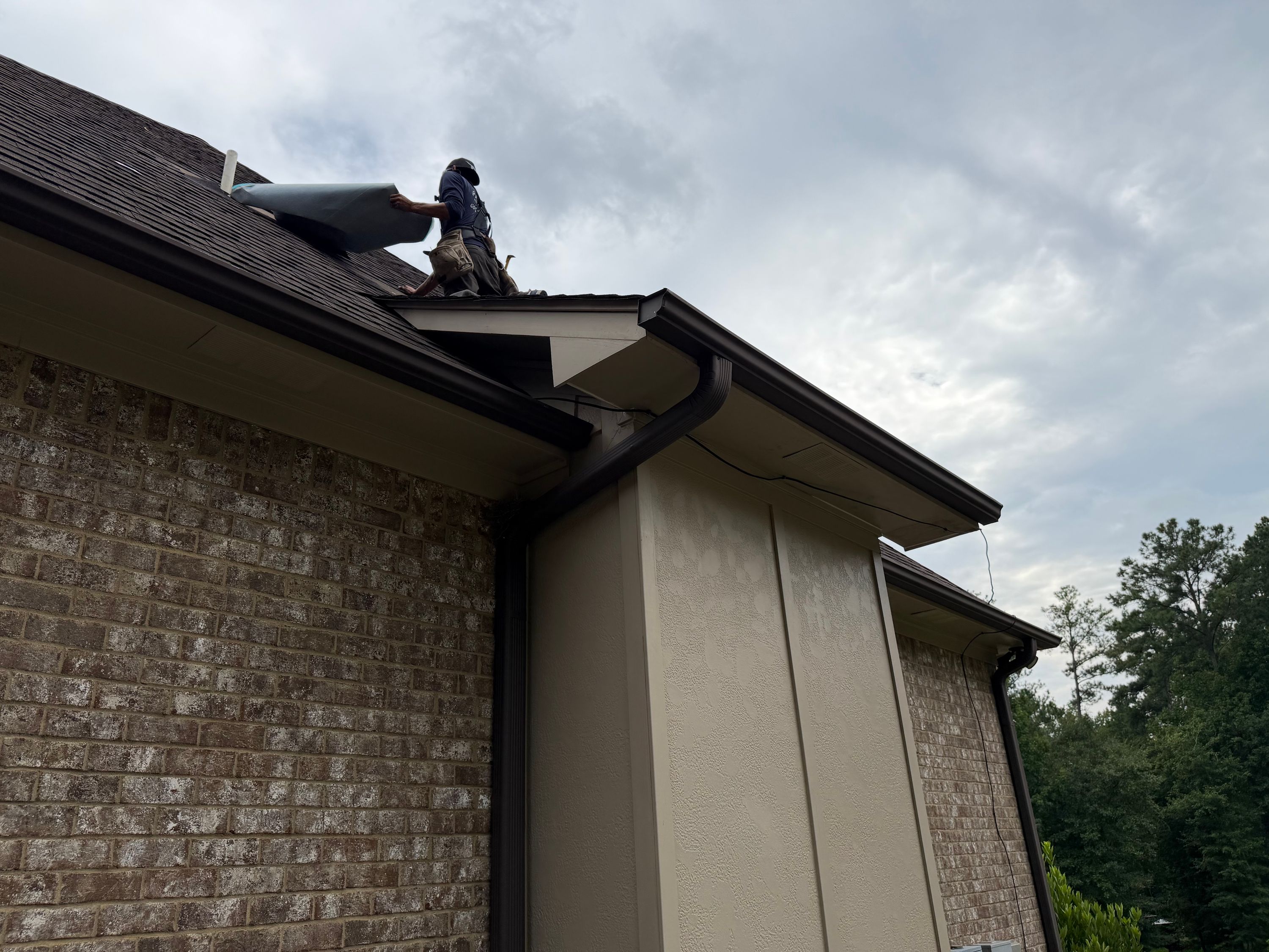 Newly installed dark brown gutter and downspout run seamlessly along the clean soffit in Chelsea.