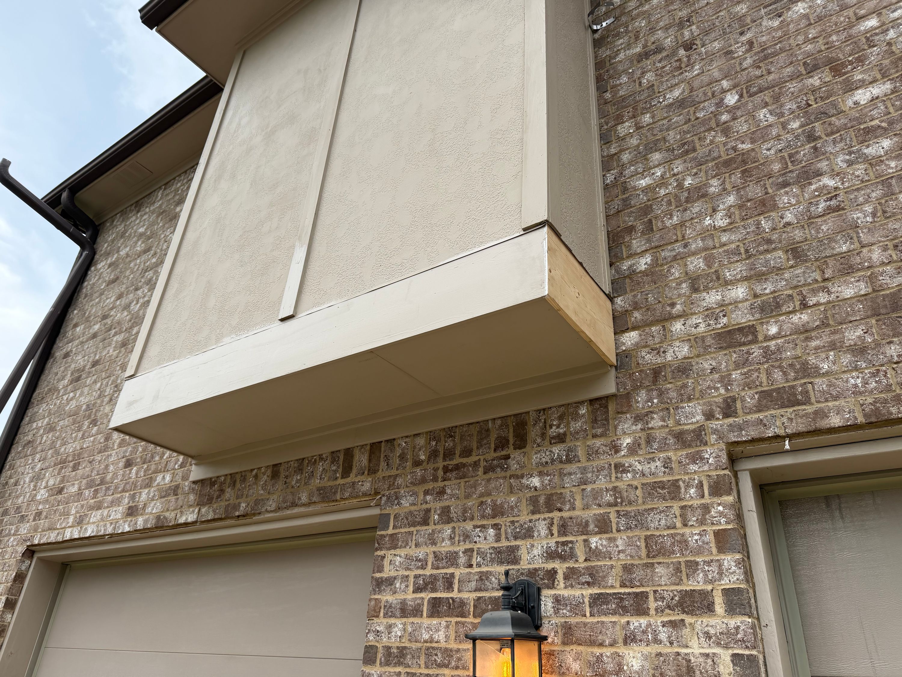 Clean trim transitions define the border between stucco siding and brick on this residential exterior.