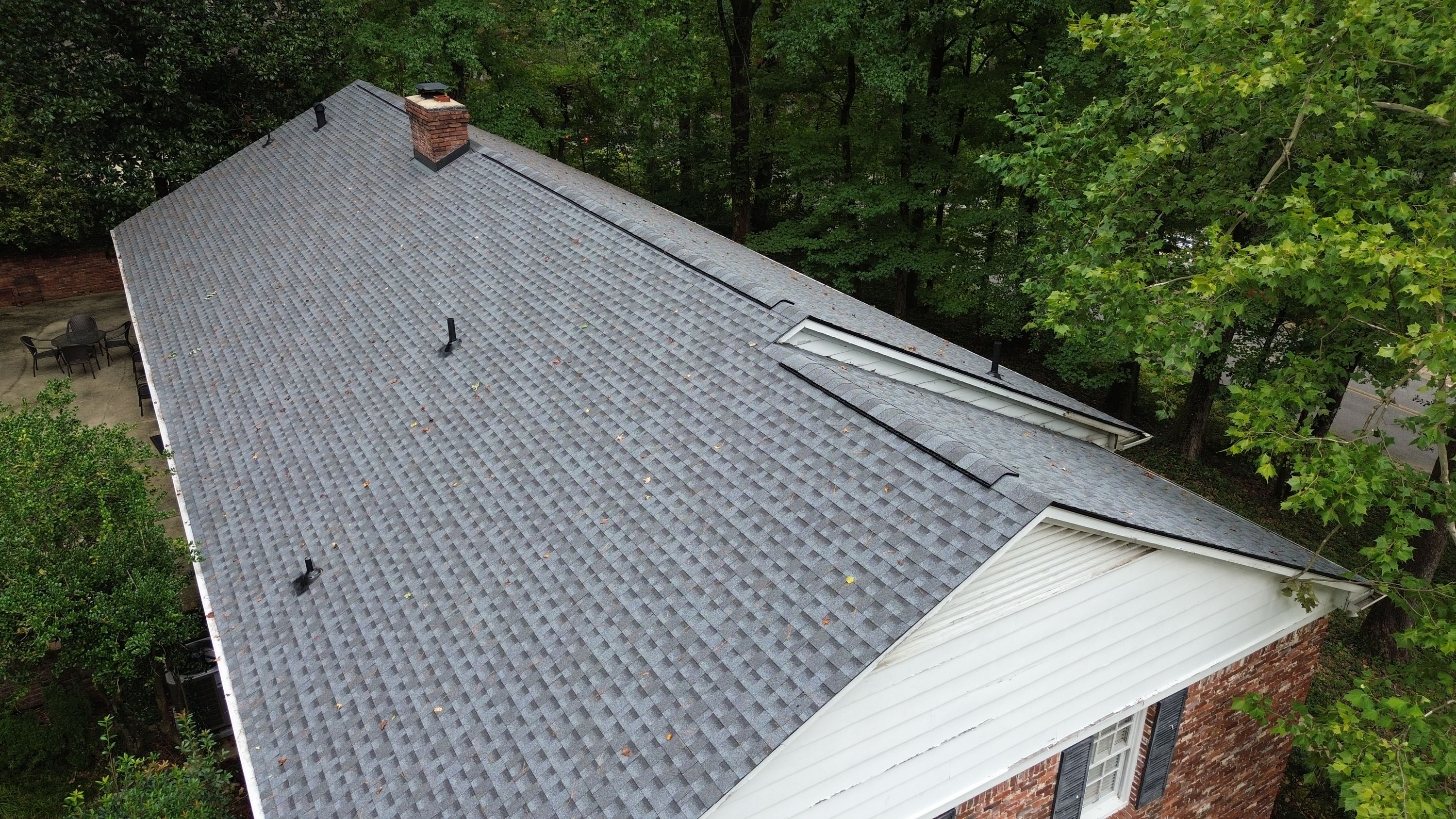 White trim framing a roof transition on a freshly completed grey shingle roof replacement in Mountain Brook.