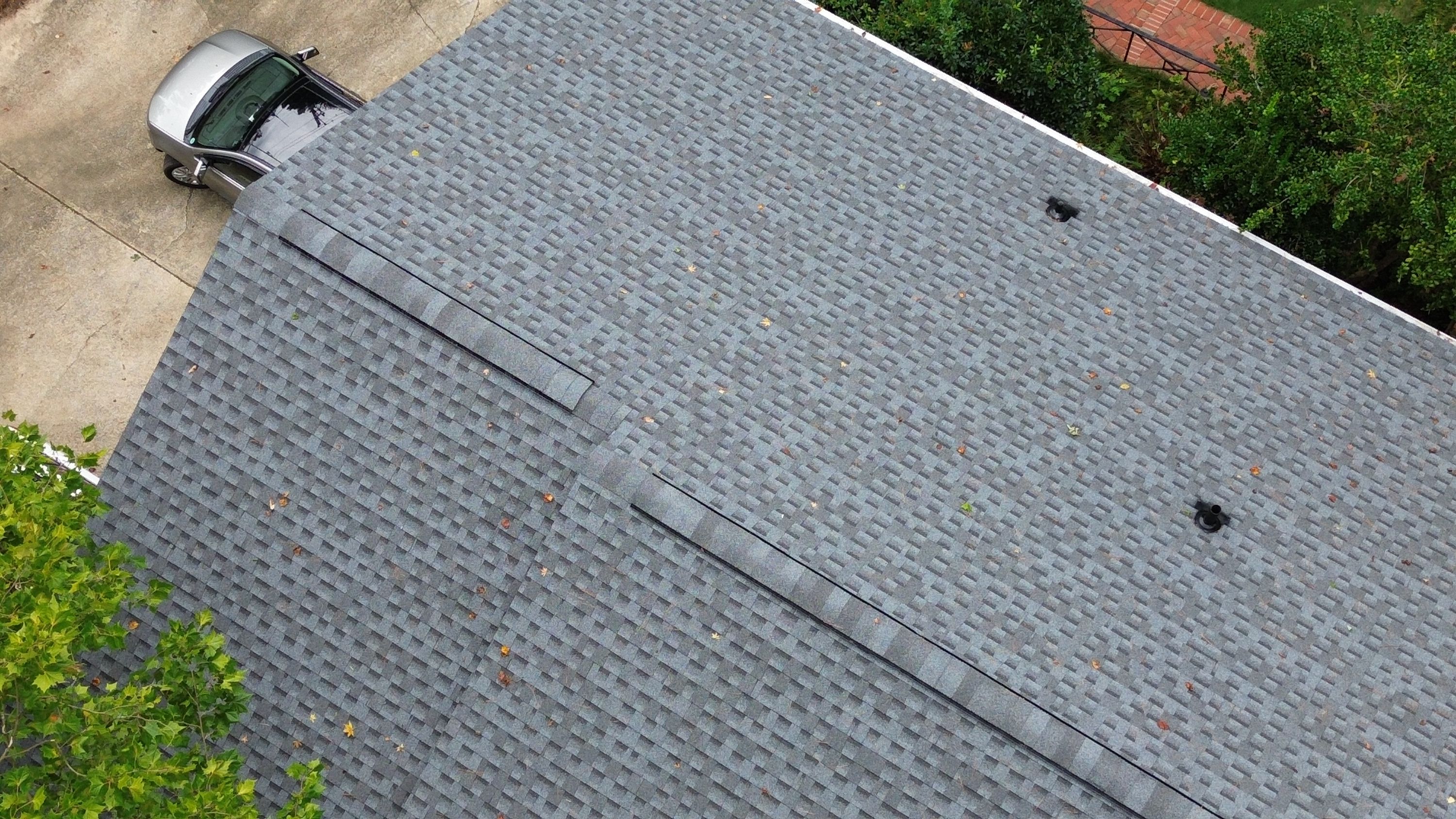 Detailed view of a newly installed ridge cap vent on a grey shingle roof slope.