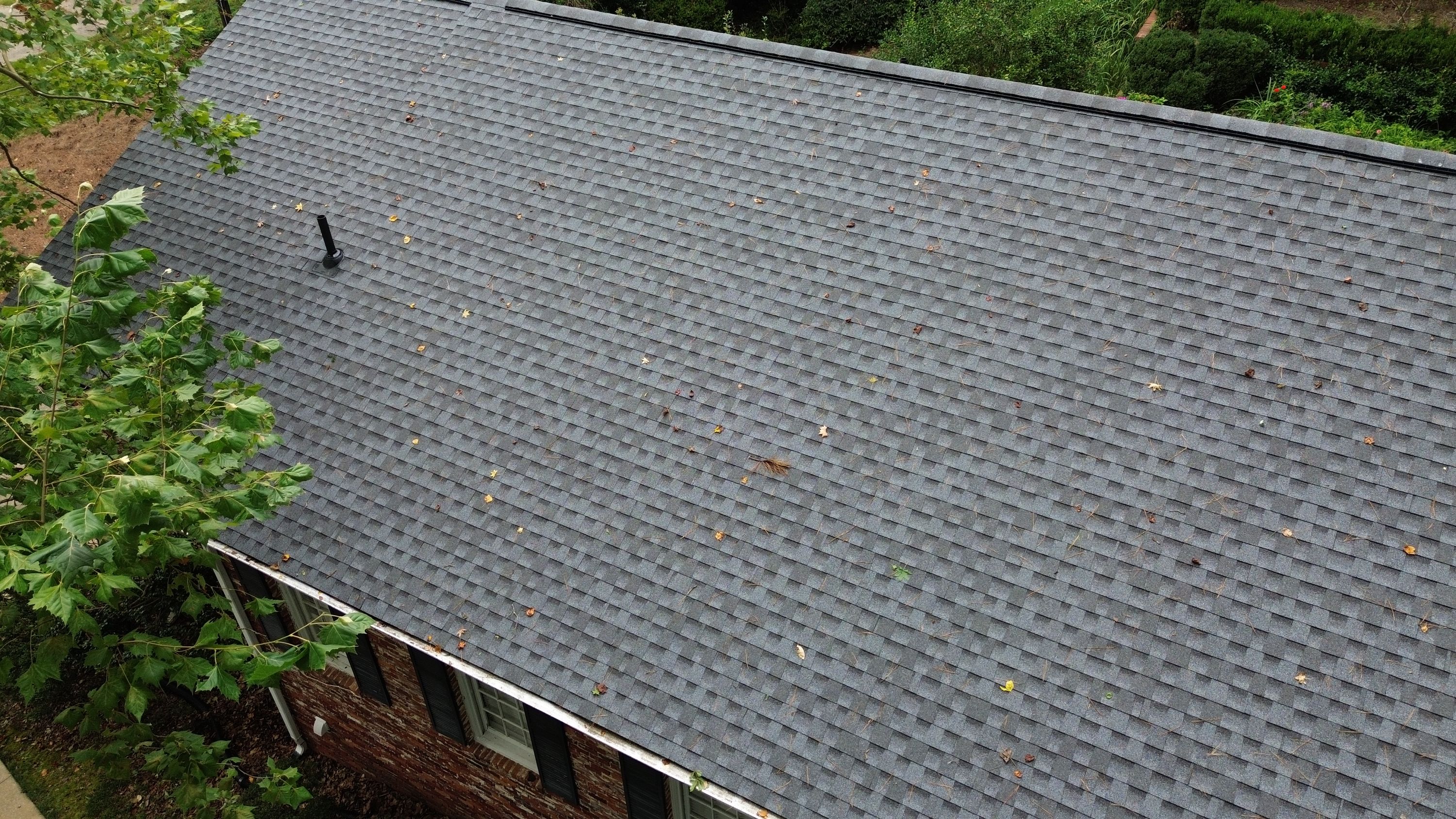Gutter guards installed along the eave of a newly shingled roof protect the home from falling leaves.