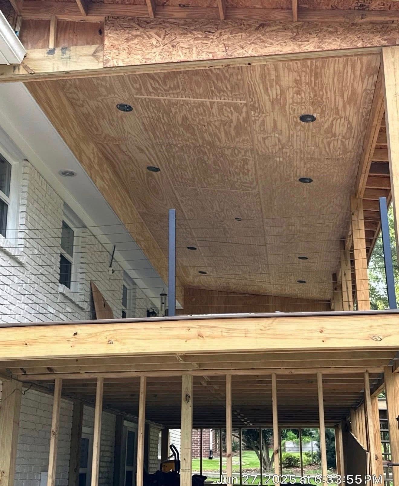 Construction phase showing the plywood ceiling and recessed lighting installation for a custom porch in Vestavia North.