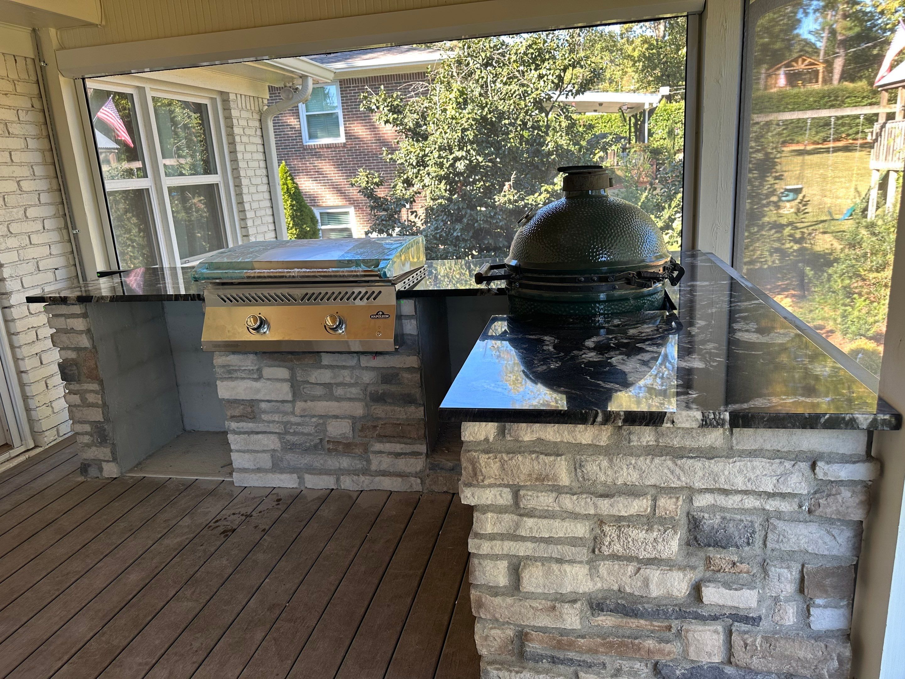 Outdoor kitchen area on a custom deck featuring granite countertops, stone masonry, and a built-in grill in Vestavia Hills.
