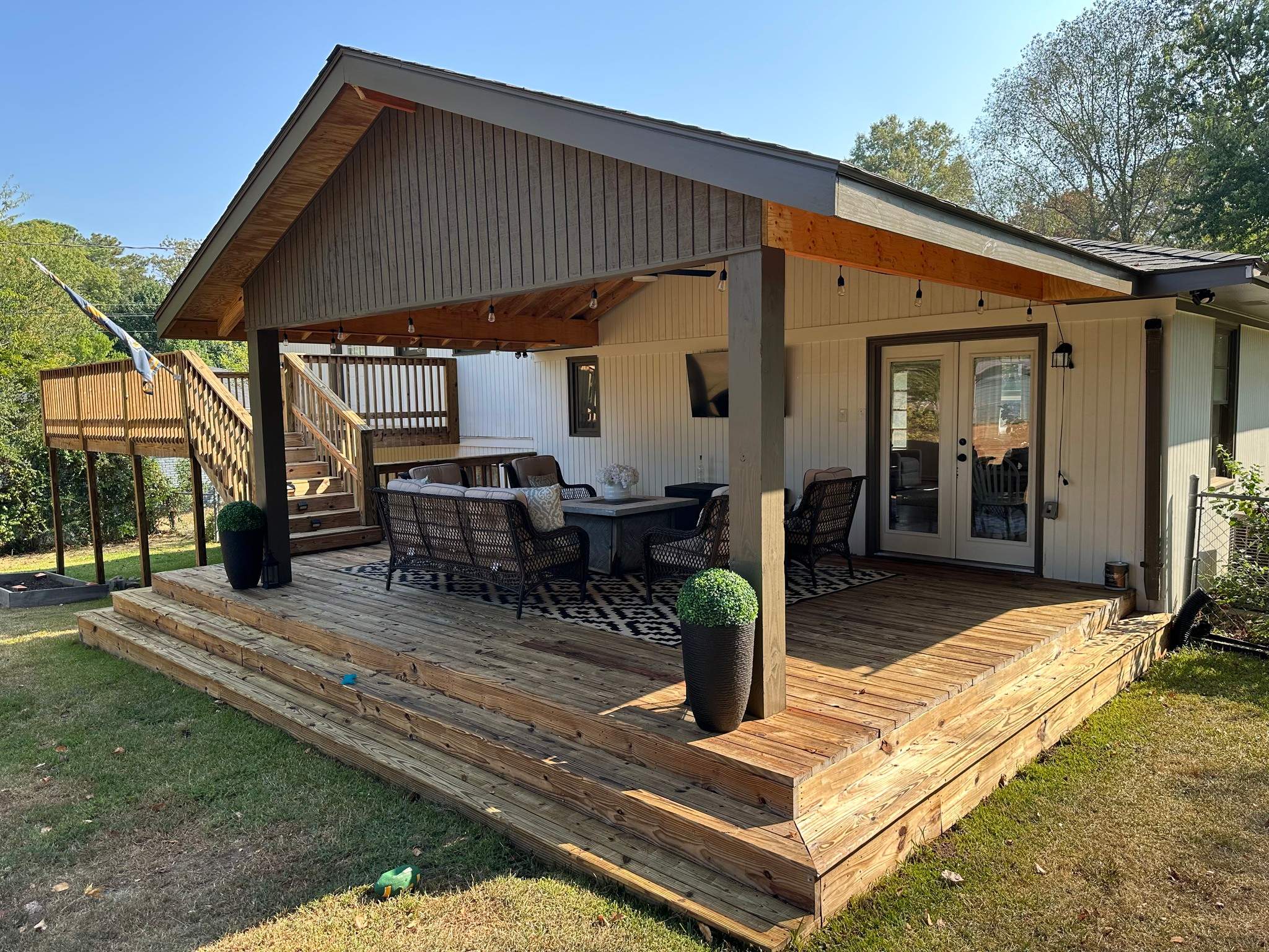 A spacious custom wooden deck in Bluff Park with a large gabled roof cover and comfortable outdoor furniture for hosting guests.