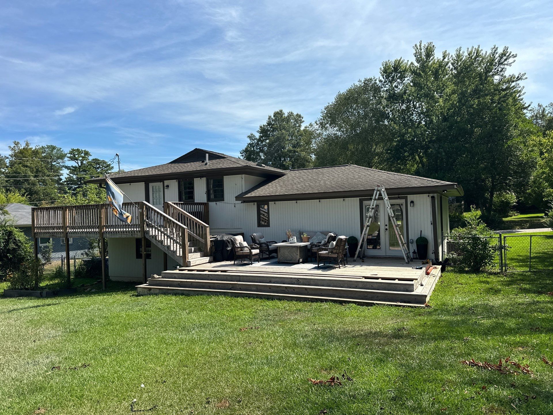 Wide-angle view of a residential home in Hoover, Alabama, during the construction phase of a custom tiered wooden deck and outdoor living area.