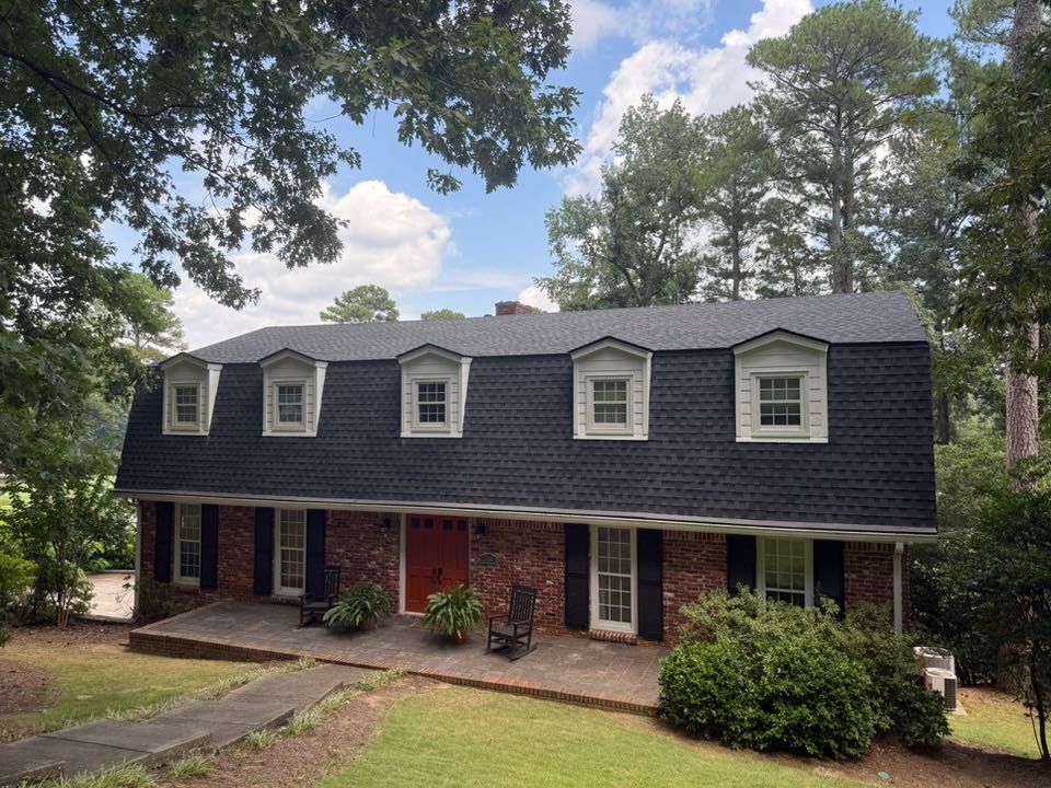 Final result of a professional roof replacement in Hoover, Alabama, showcasing new dark architectural shingles on a two-story brick house.
