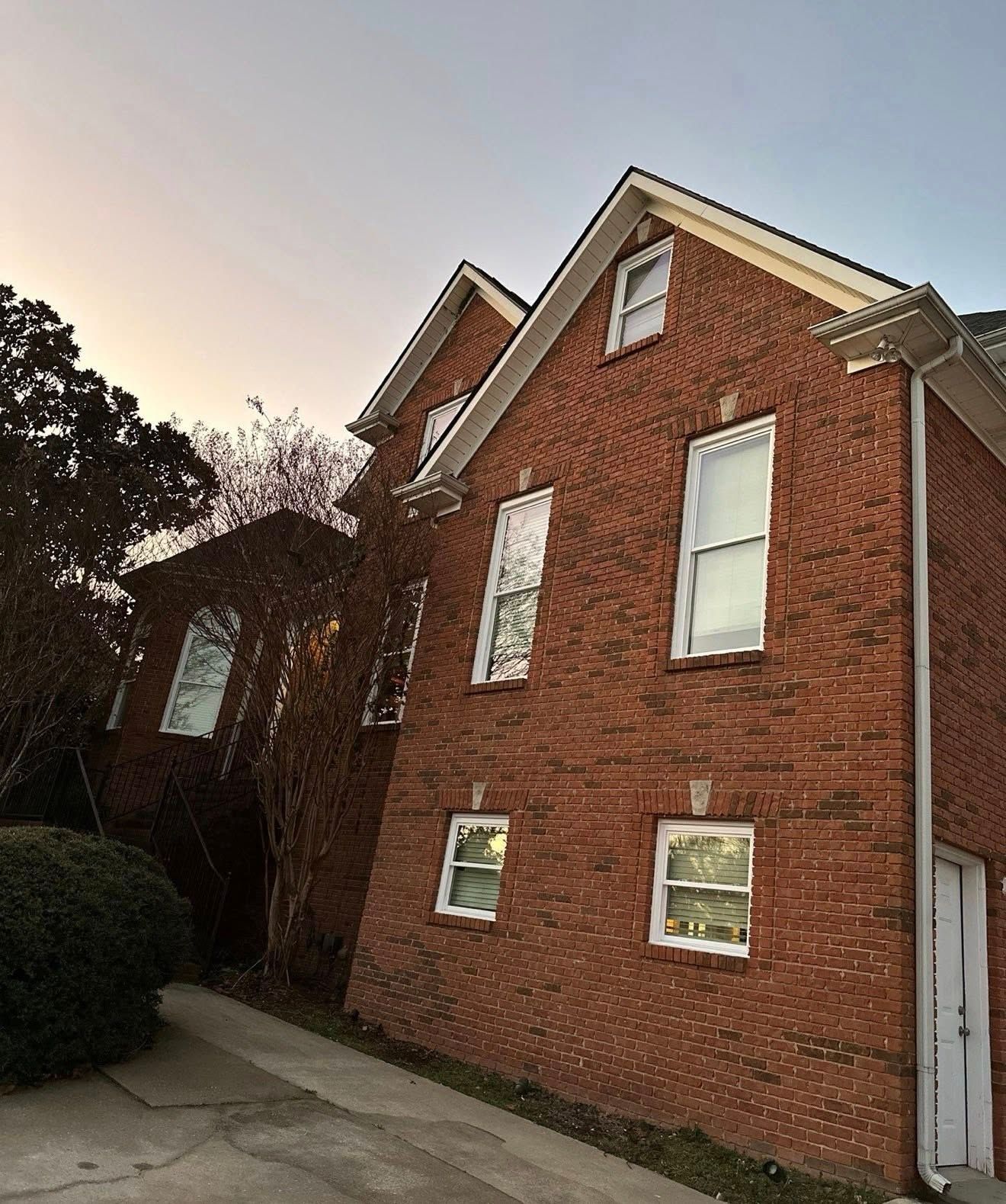 New white-trimmed windows installed on a multi-story brick residence in Hoover, Alabama.