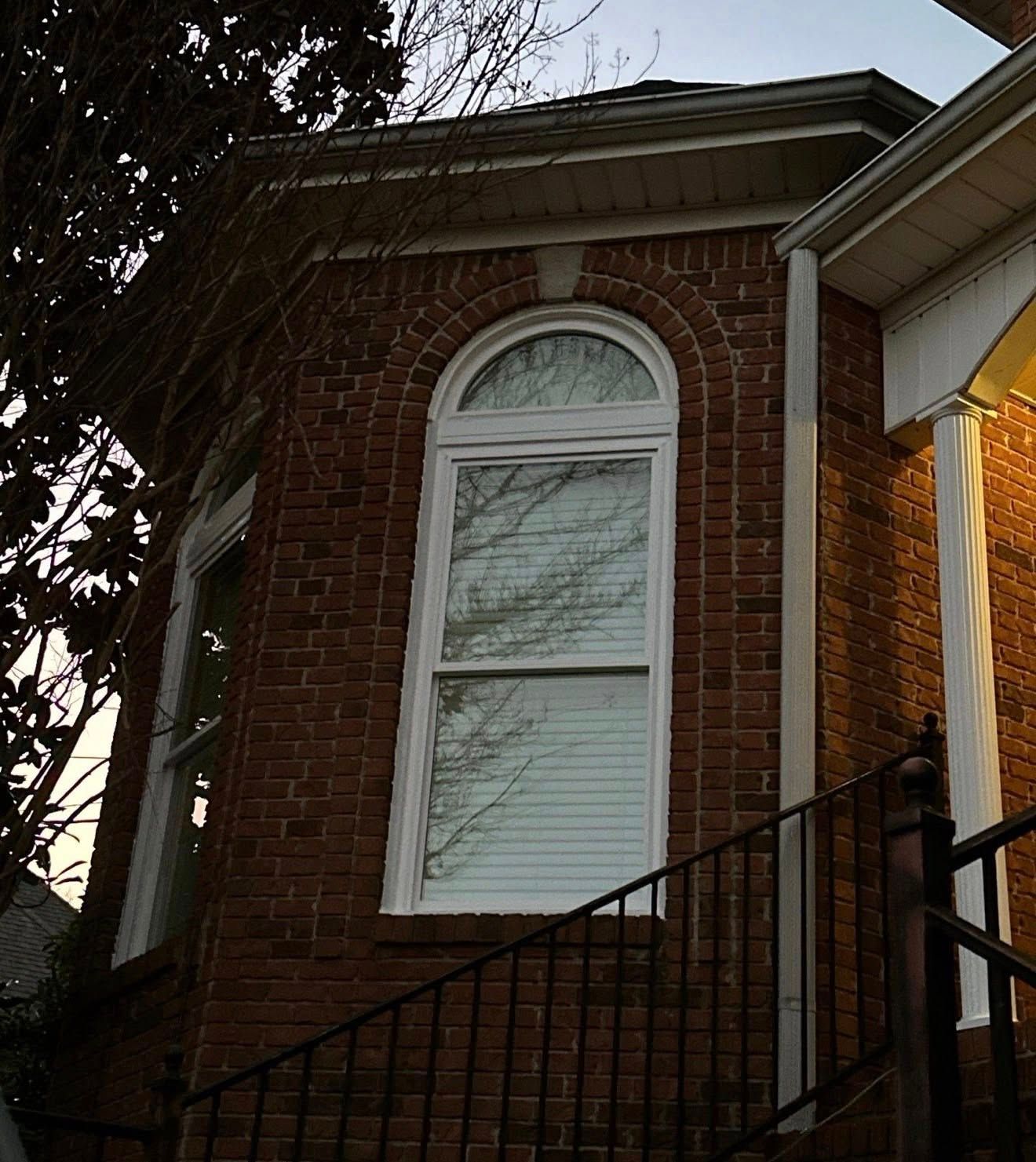 Arched white vinyl window replacement on a red brick home in Hoover, Alabama.